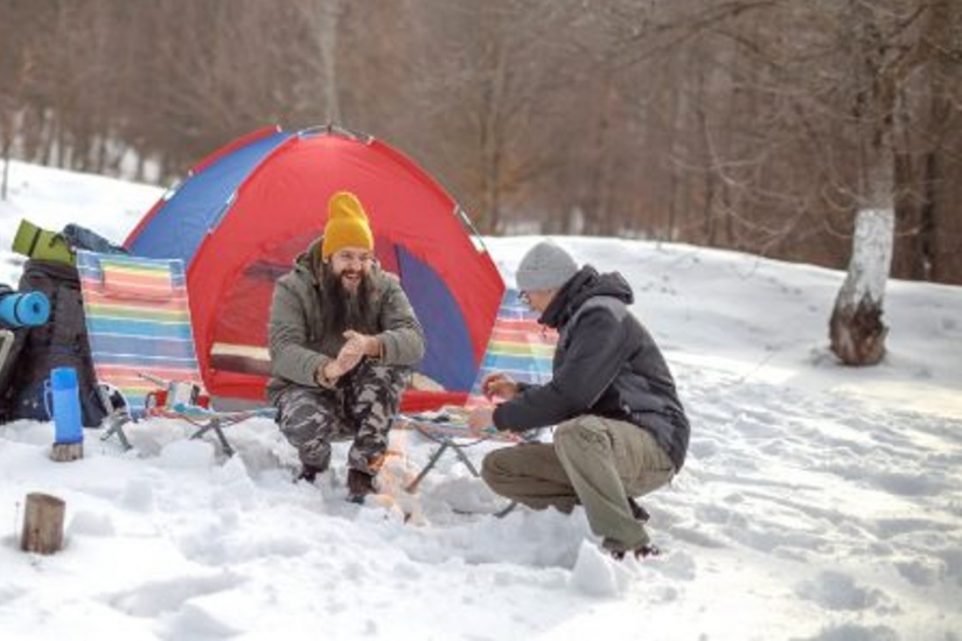 Two male friends hiking and camping on snow