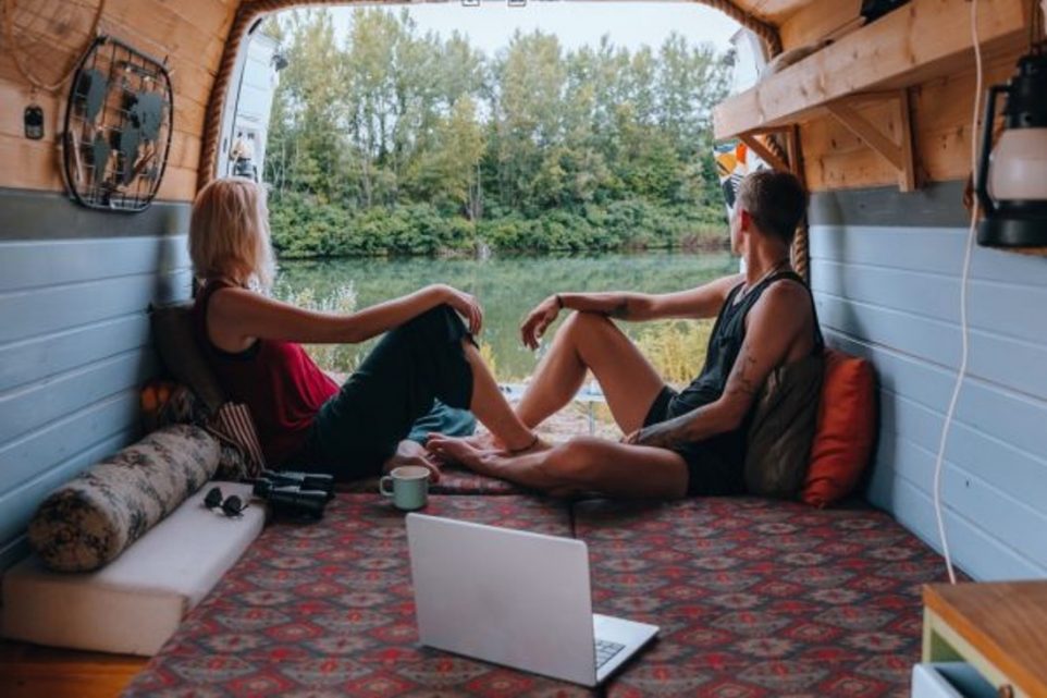 Couple in back of camper looking at outdoor scenery