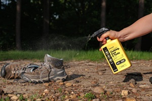 A man sprays a shoe with Sawyer Products Tick Repellent, providing protection against ticks for his outdoor adventure.